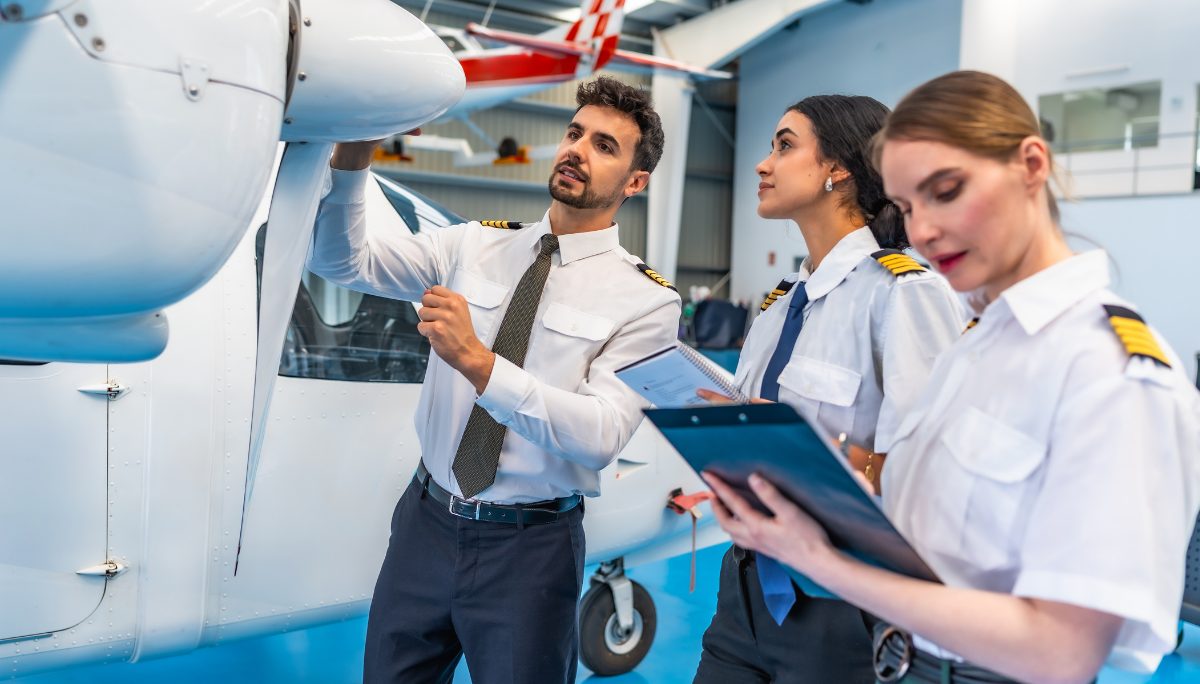 Mastering Technical Knowledge for High-Level Aviation Interviews Three pilot candidates examining an aircraft and taking notes during a training or preflight evaluation.