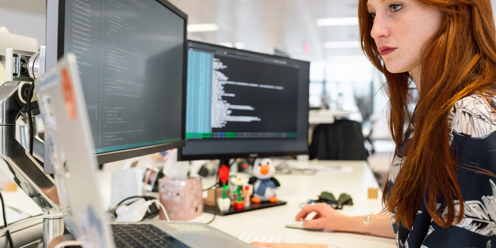 Professional woman focused on computer screens in a modern office environment