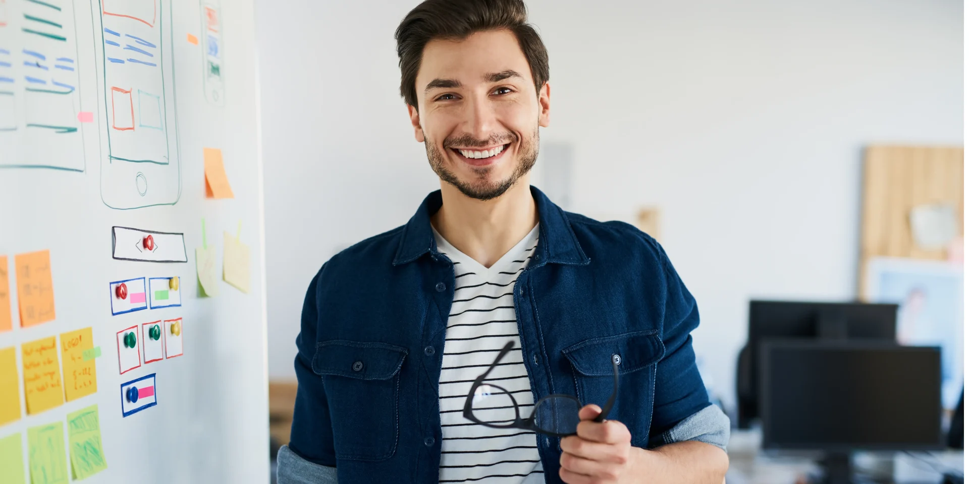 Smiling professional standing near a whiteboard in a modern office environment