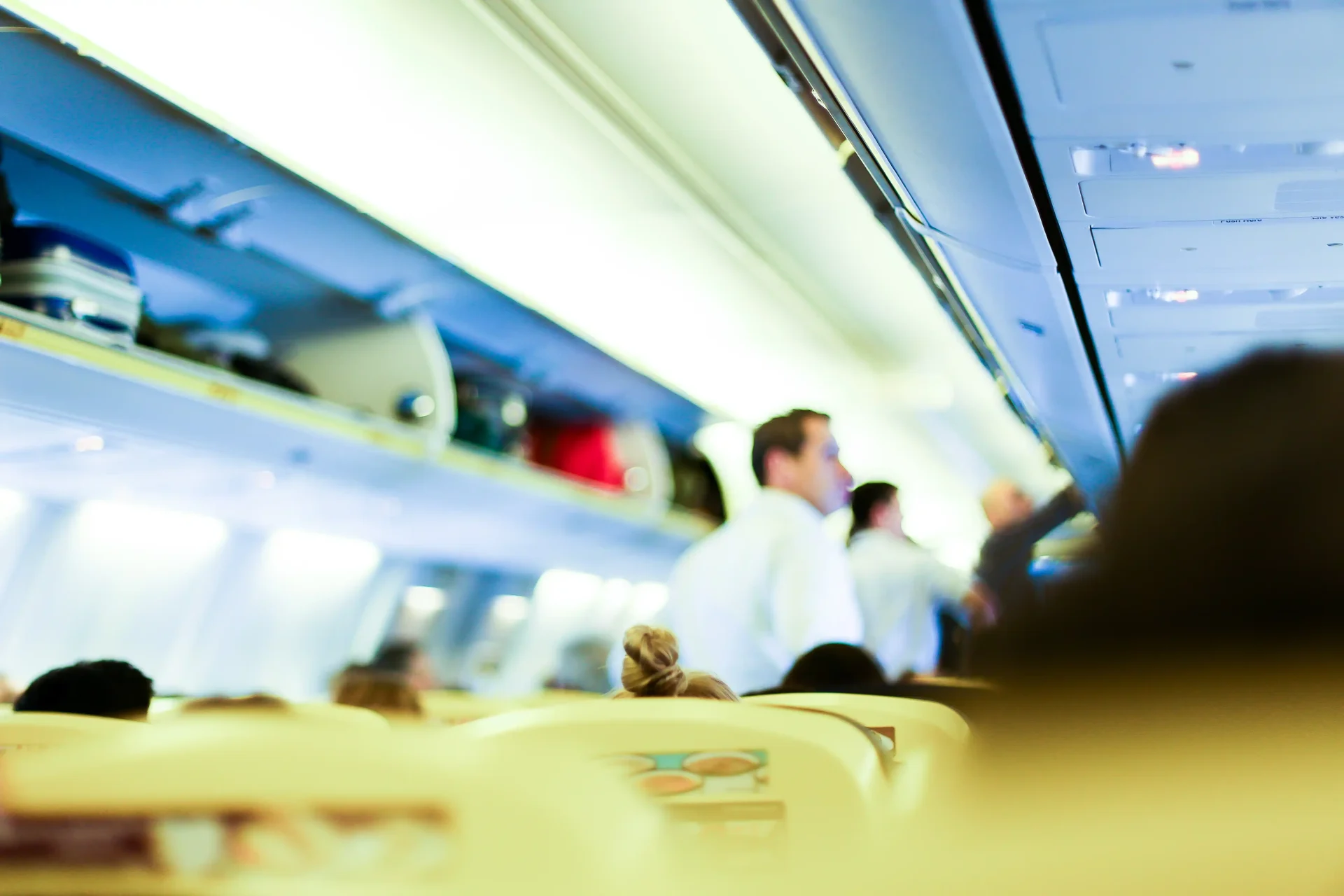 Flight attendant video interview: blurred airplane cabin Blurred airplane cabin with flight attendants in the aisle, passengers seated and bags stowed in overhead bins